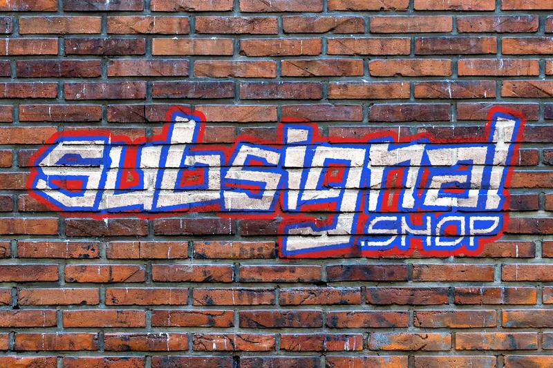 The wordmark painted as graffiti on a brick wall in white, blue and red