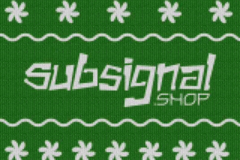White letters knitted into a green holiday sweater with snowflakes